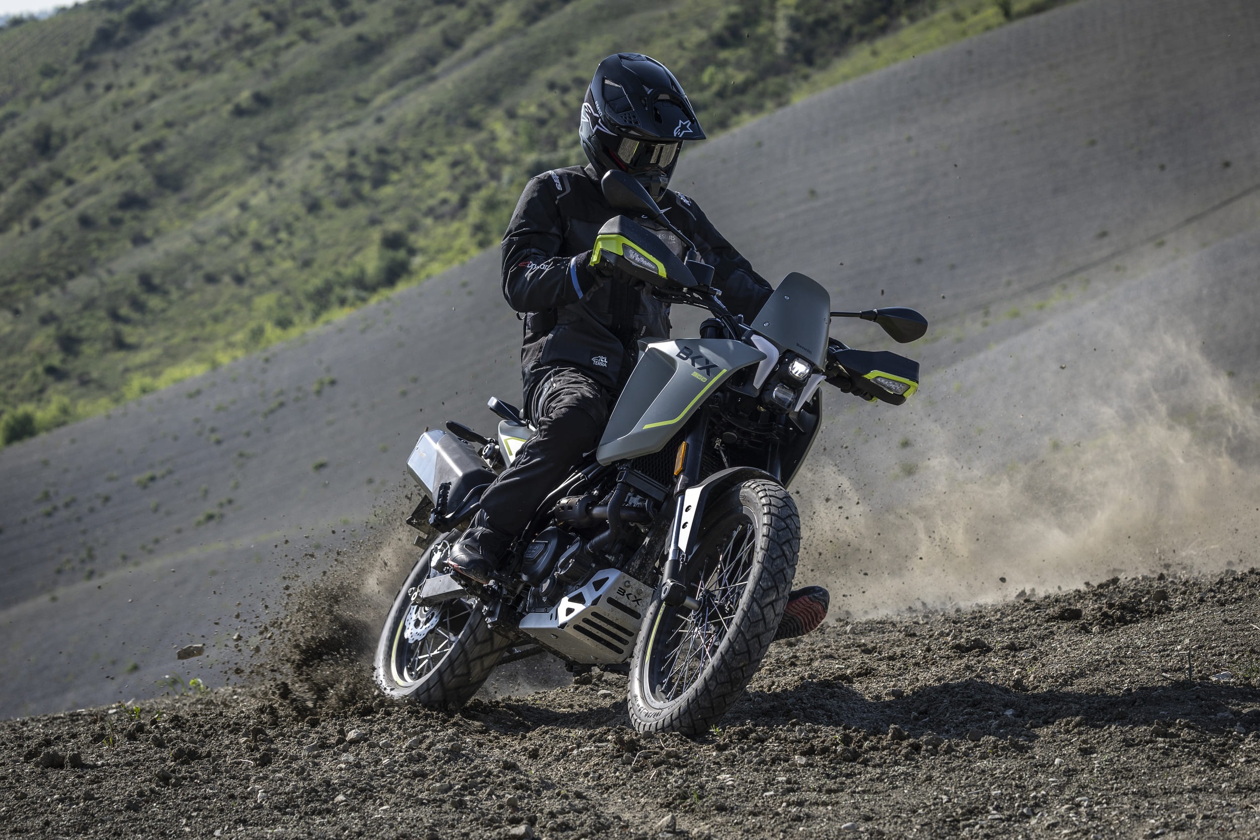 Benelli-bkx-300 1 - AutoBike Motorcyclist in black gear riding a dual-sport bike on a dusty off-road slope, kicking up dirt and gravel behind him. - AutoBike