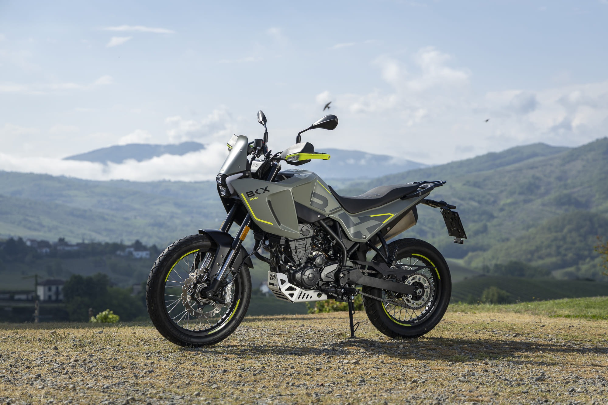 Benelli-bkx-300 2 - AutoBike Adventure motorcycle with lime-yellow accents on a gravel path, mountains in the background. - AutoBike