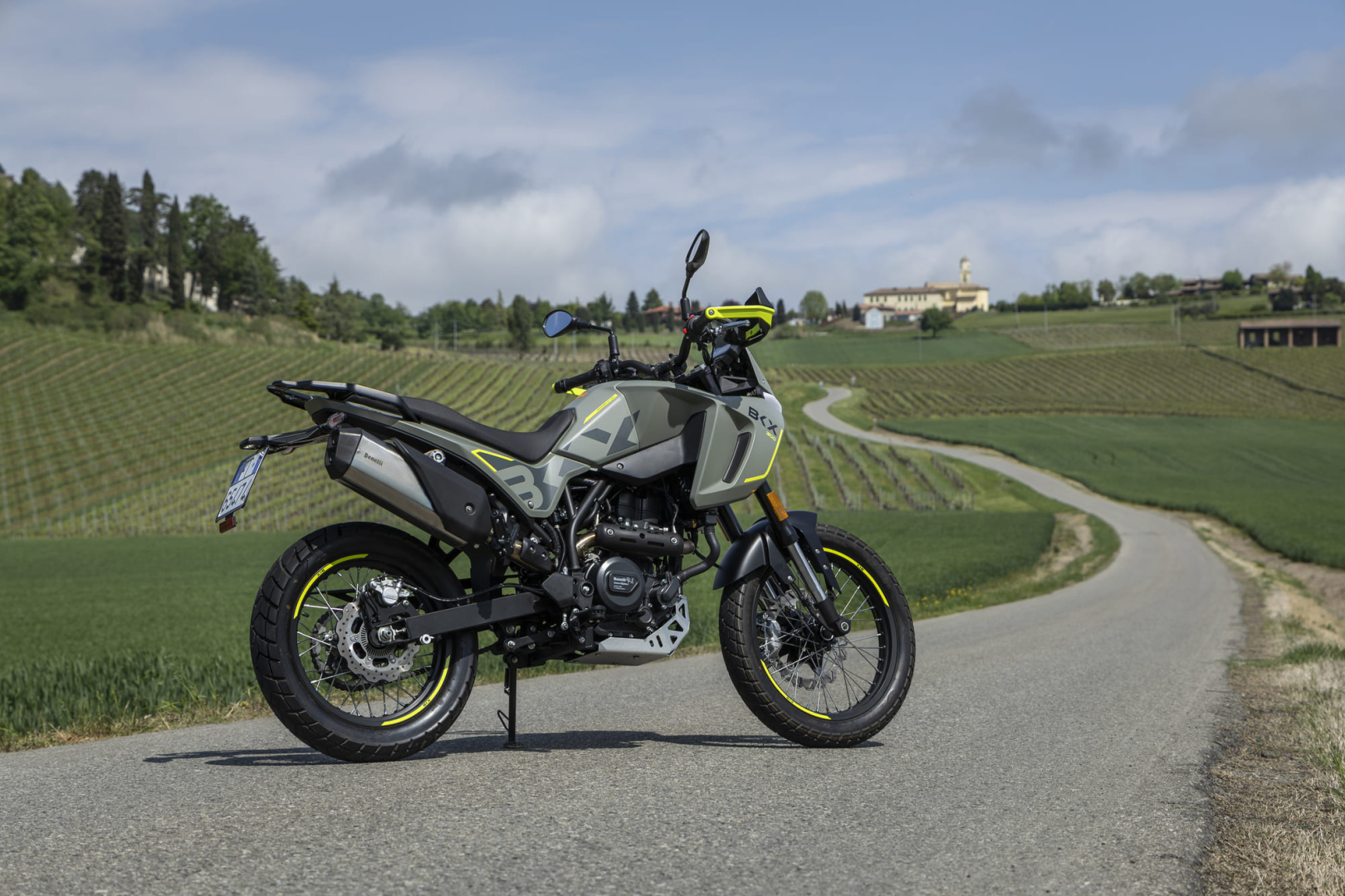 Benelli-bkx-300 4 - AutoBike Adventure motorcycle parked on a winding country road with vineyards in the background and a yellow-green accent bike helmet on the handlebars. - AutoBike