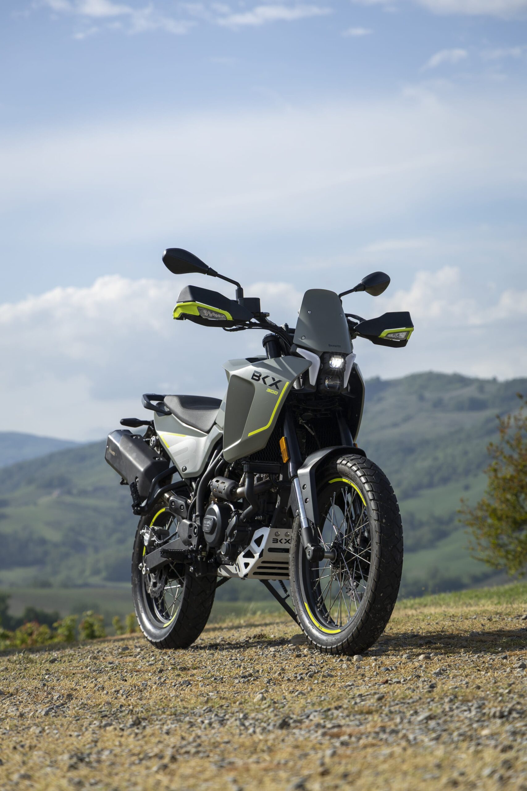 Benelli-bkx-300 - AutoBike Adventure motorcycle parked on a rocky dirt road with rolling hills and blue sky in the background - AutoBike