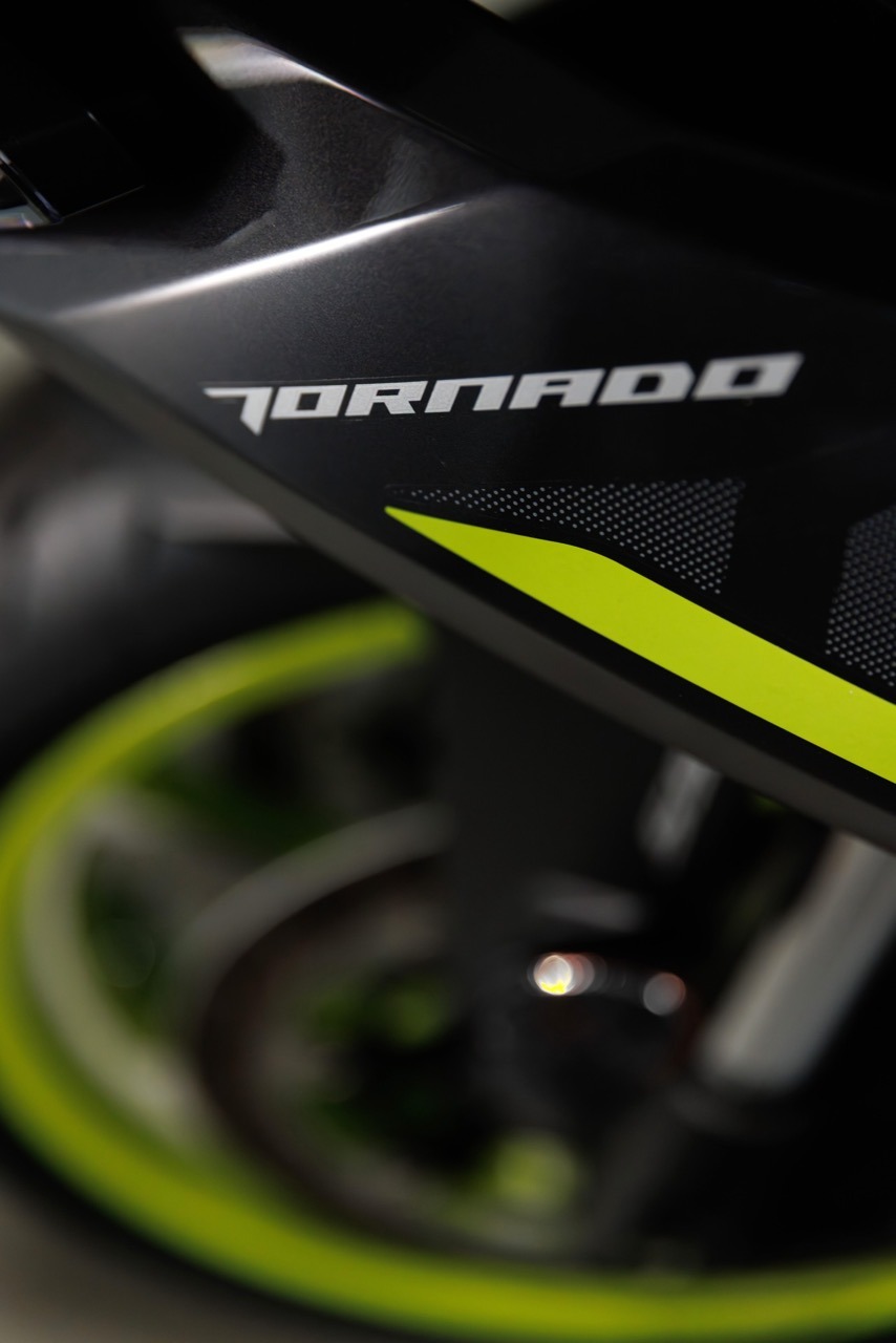 Benelli-tornado-550 2 - AutoBike Close-up of a black motorcycle fairing with the word 'TORNADO' and a neon yellow stripe. - AutoBike