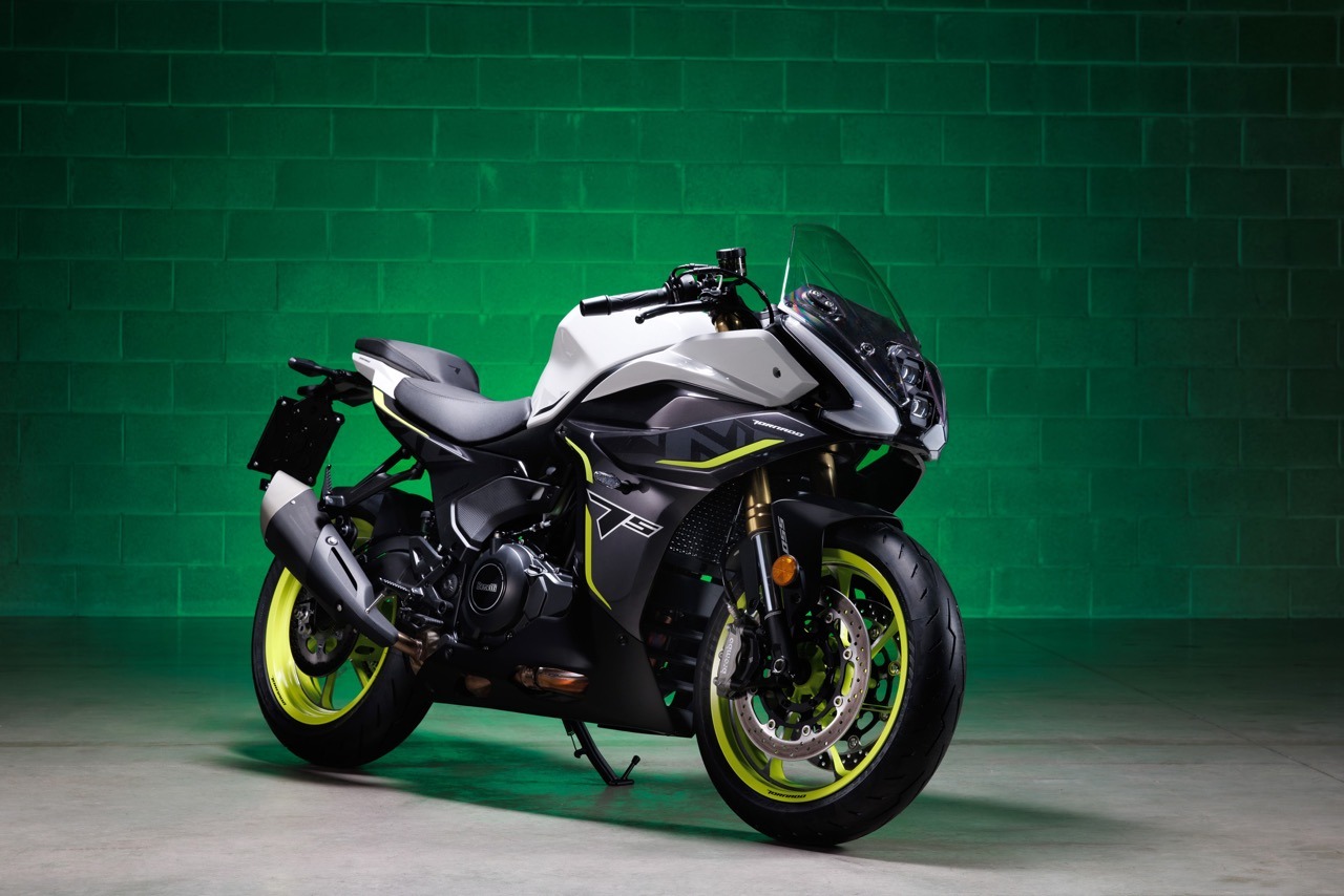 Benelli-tornado-550 4 - AutoBike Sport motorcycle with white, black and neon lime graphics, lime-green wheels, on a center stand in a green studio backdrop. - AutoBike