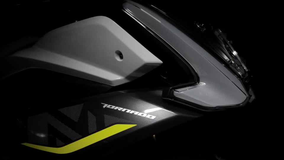 Benelli-tornado-550 5 - AutoBike Close-up of a sport motorcycle's front fairing with a yellow accent and the word 'TORNADO' on the side, headlight area visible in low light. - AutoBike