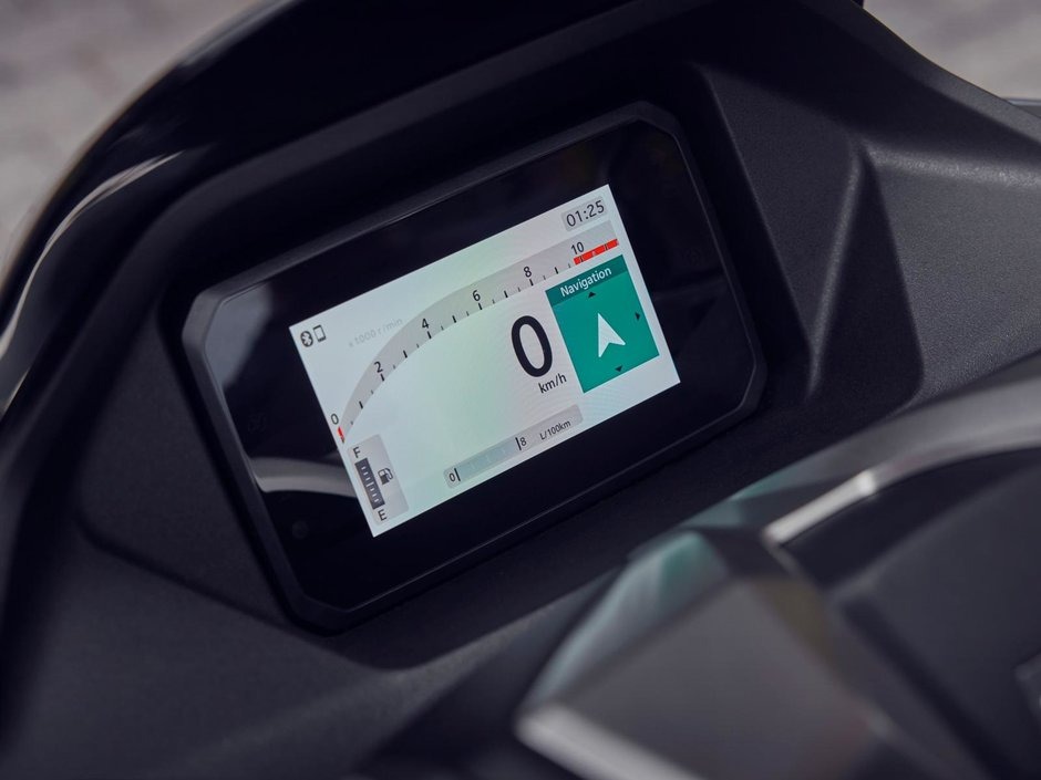 honda-pcx-125- 21 - AutoBike Digital motorcycle dashboard showing 0 km/h with a navigation indicator on the right and fuel gauge on the left. - AutoBike