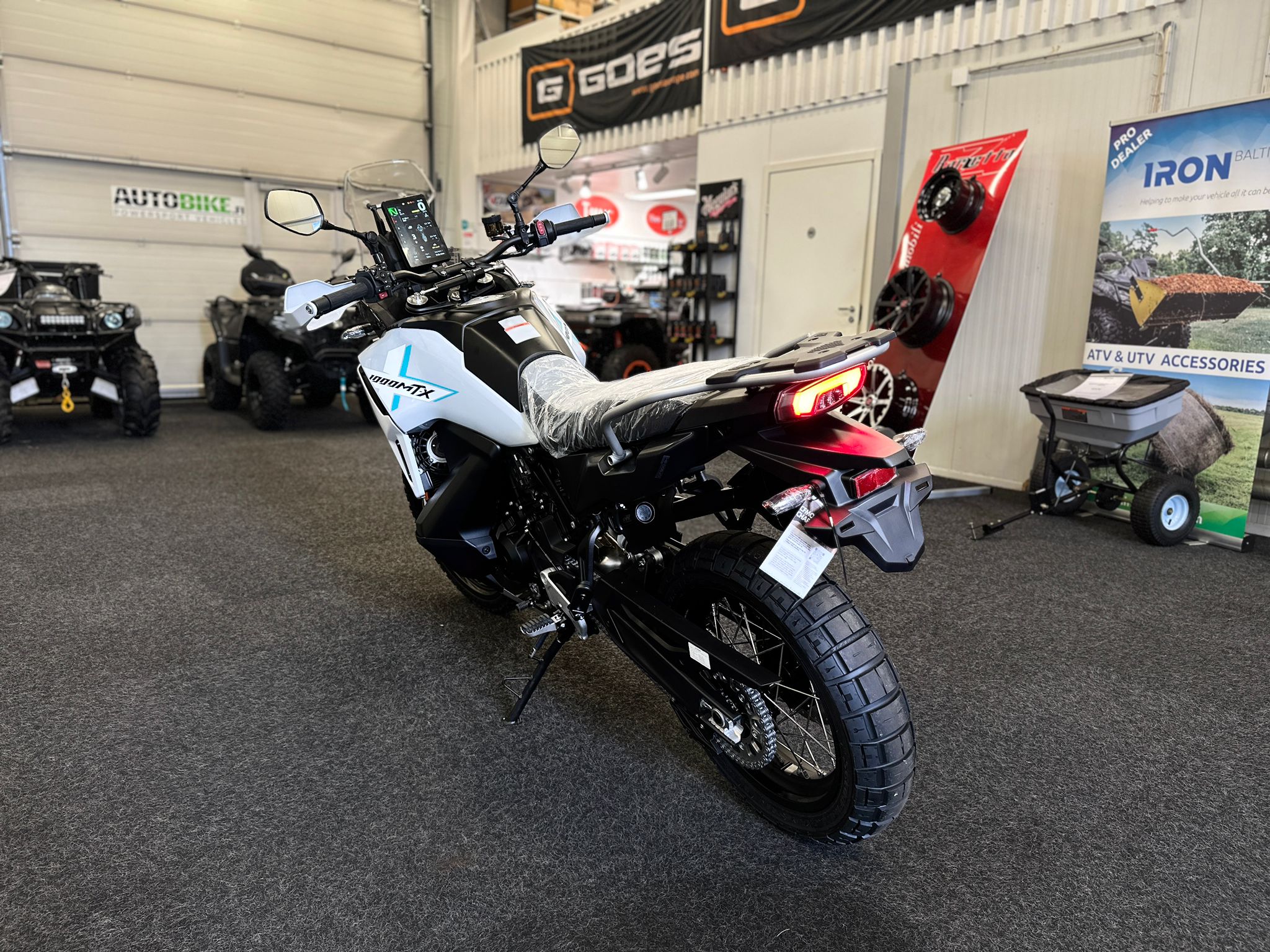 CFMOTO-1000-MT-X-1-18 at 203522 - AutoBike Motorcycle displayed indoors in a showroom with banners and accessories in the background. - AutoBike