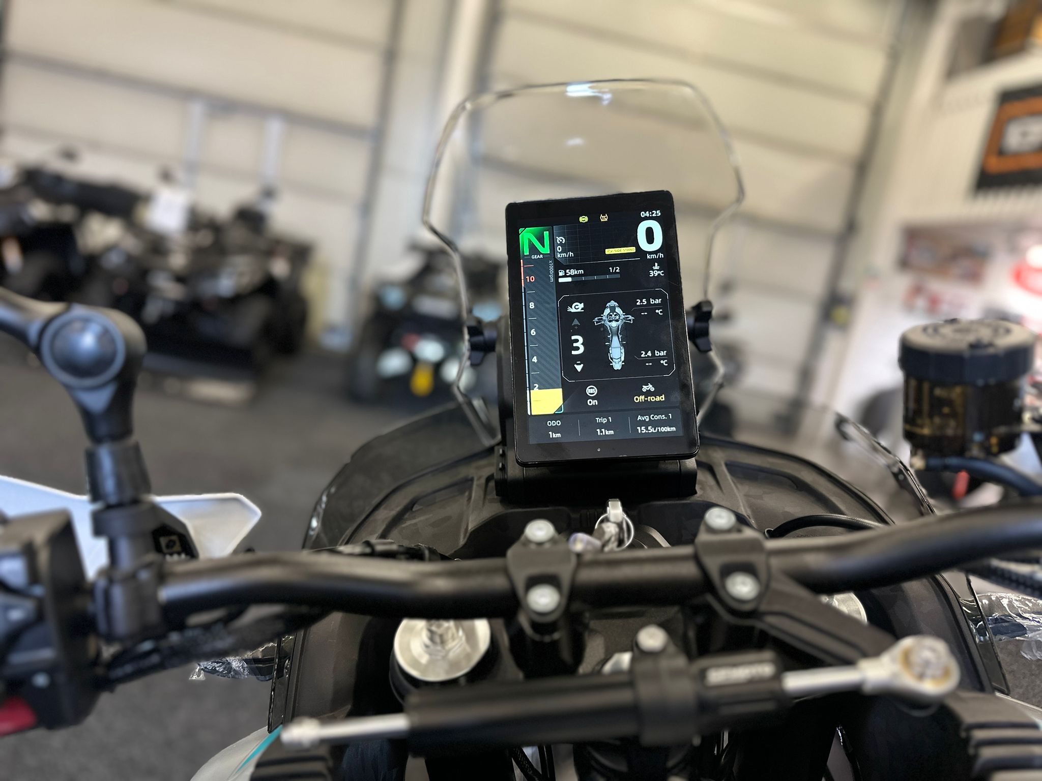 CFMOTO-1000-MT-X-1-18 at 203523 1 - AutoBike Close-up of a digital motorcycle instrument cluster mounted on the handlebars, displaying gear, speed, and ride data. - AutoBike