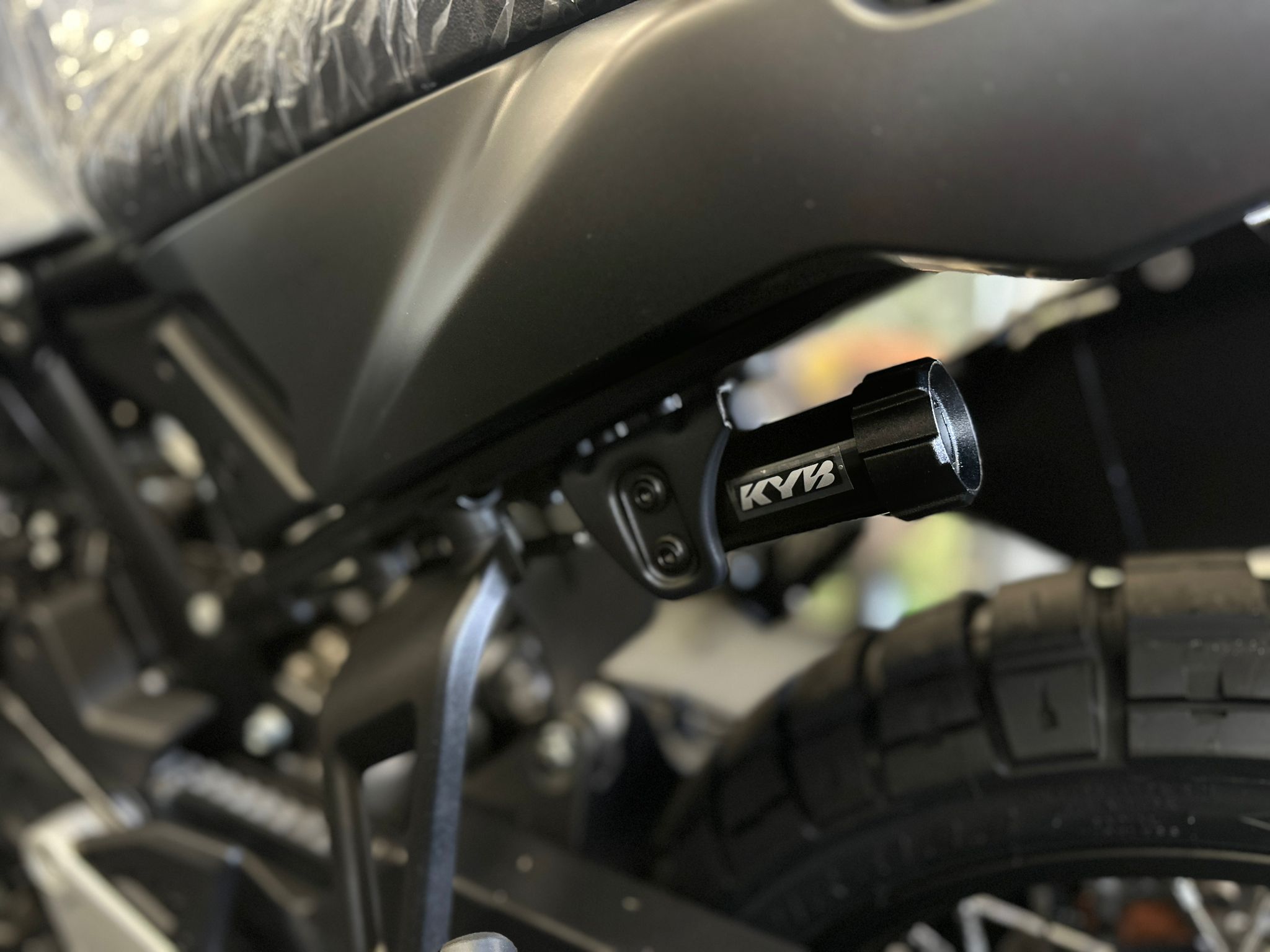 CFMOTO-1000-MT-X-1-18 at 203525 2 - AutoBike Close-up of a motorcycle rear shock absorber area with a KYB component mounted to black frame. - AutoBike