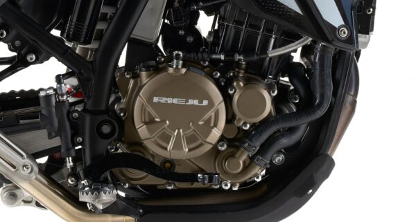 Close-up of a gold RIEJU motorcycle engine cover, with hoses and frame surrounding it. - AutoBike