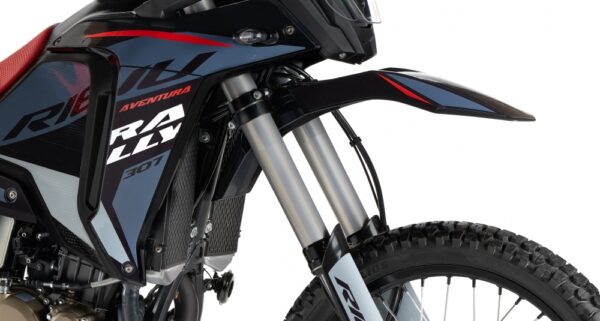 Close-up of a black and blue adventure motorcycle front end, showing twin suspension forks, knobby tire, and angular body panels with red accents. - AutoBike