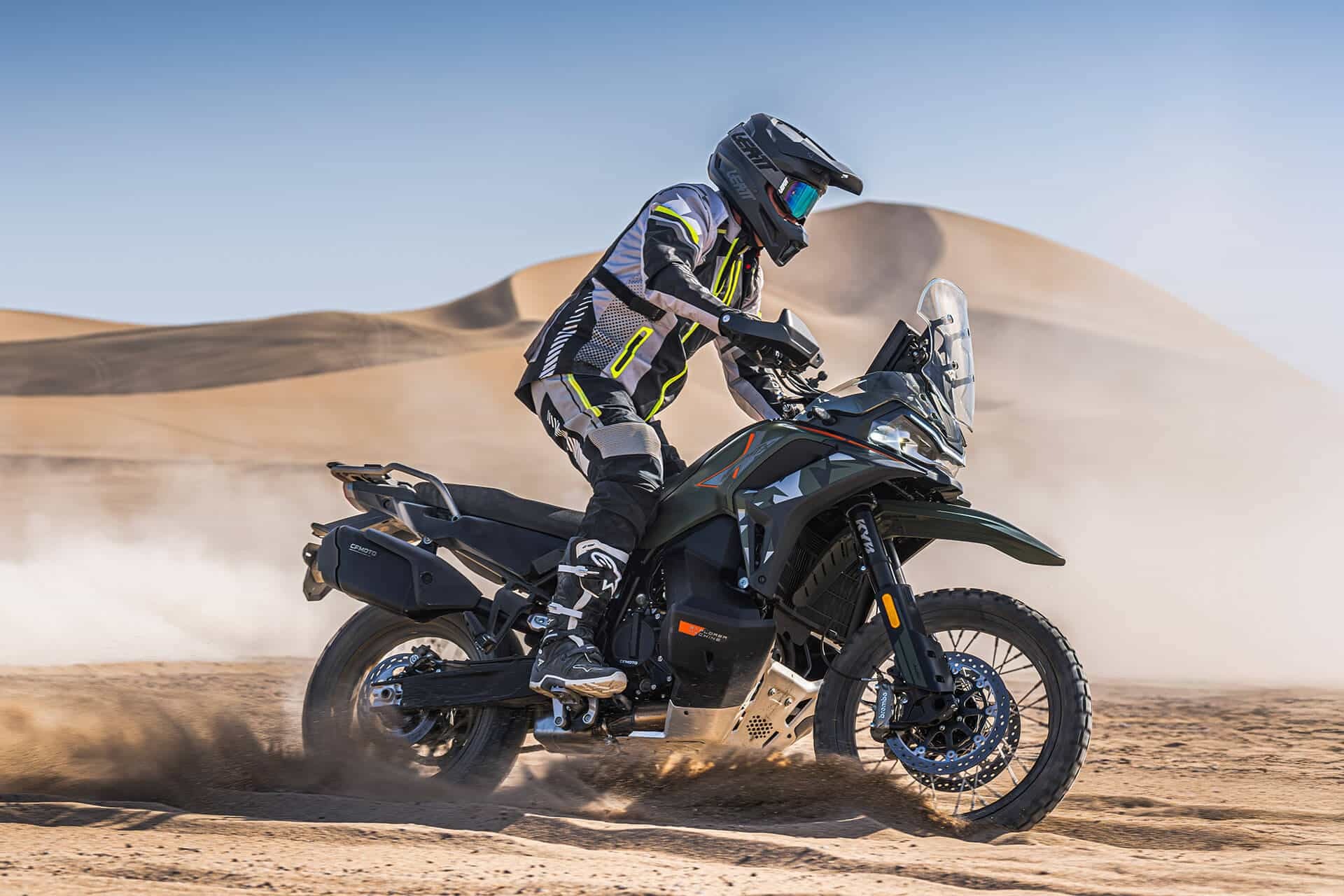 rieju-xplora-707-x - AutoBike Motorcyclist in full gear riding a rugged dual-sport bike across sandy desert dunes, kicking up dust - AutoBike