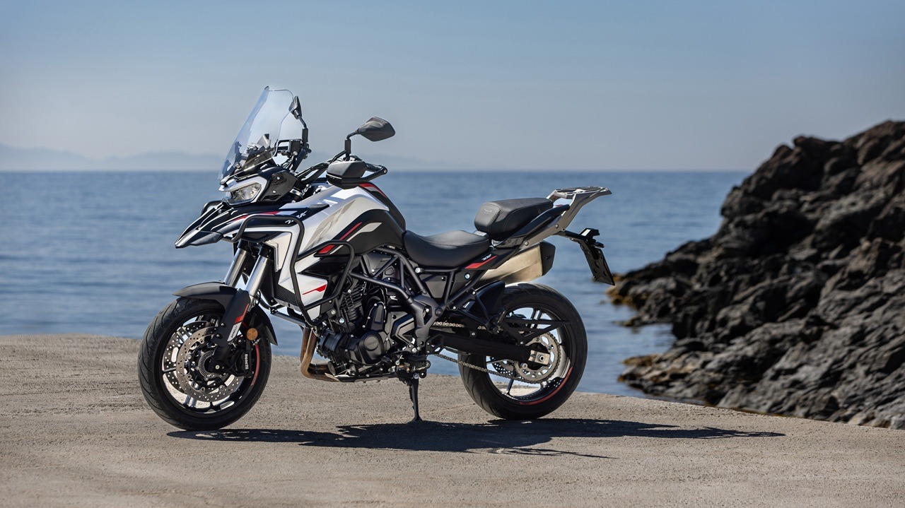 Benelli-trk-702 10 - AutoBike White and black adventure motorcycle parked on a concrete jetty by the sea with rocky shore to the right. - AutoBike