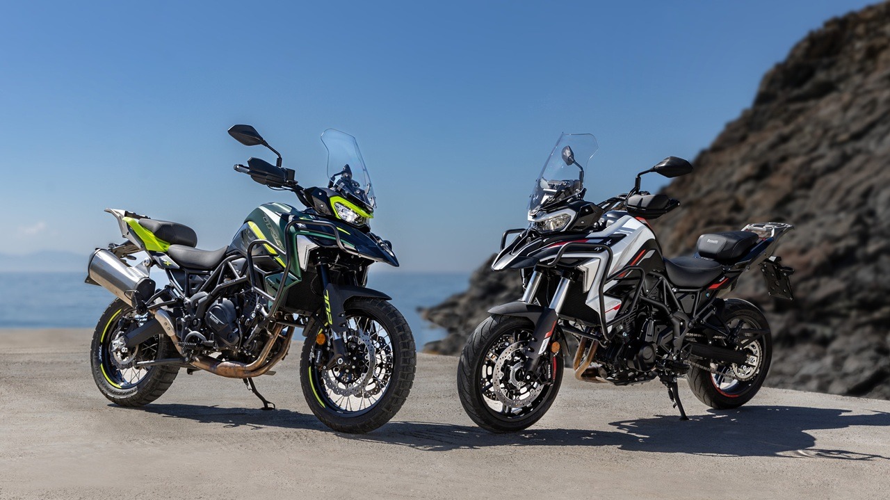 Benelli-trk-702 12 - AutoBike Two adventure motorcycles parked on a sandy beach with a rocky cliff and the blue ocean in the background. - AutoBike