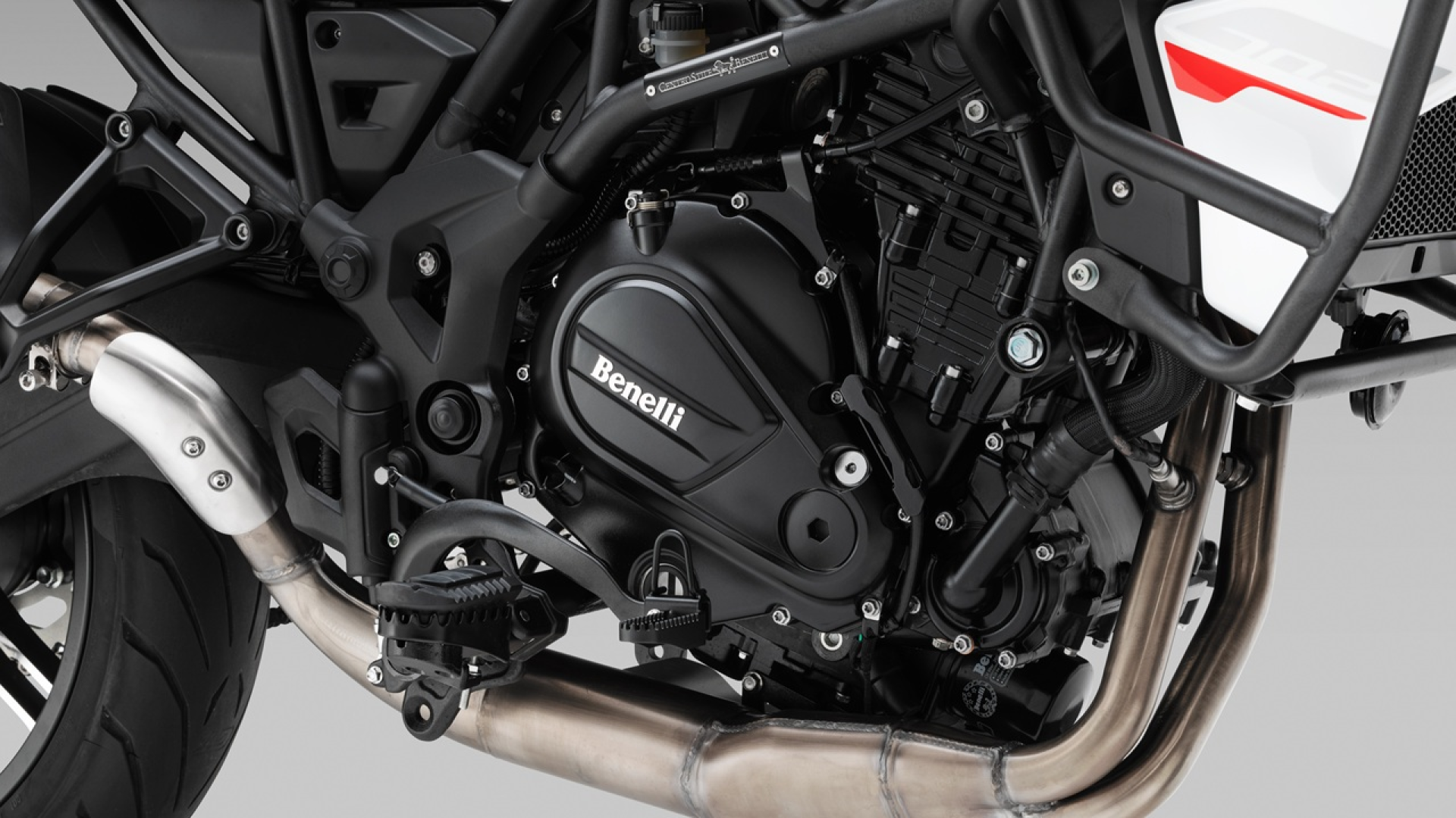 Benelli-trk-702 2 - AutoBike Close-up of a Benelli motorcycle engine and exhaust with frame and cooling fins visible. - AutoBike