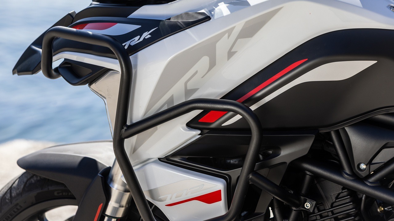 Benelli-trk-702 9 - AutoBike Close-up of a white and black sport motorcycle with protective crash bars and red accent graphics near the fuel tank edge. - AutoBike