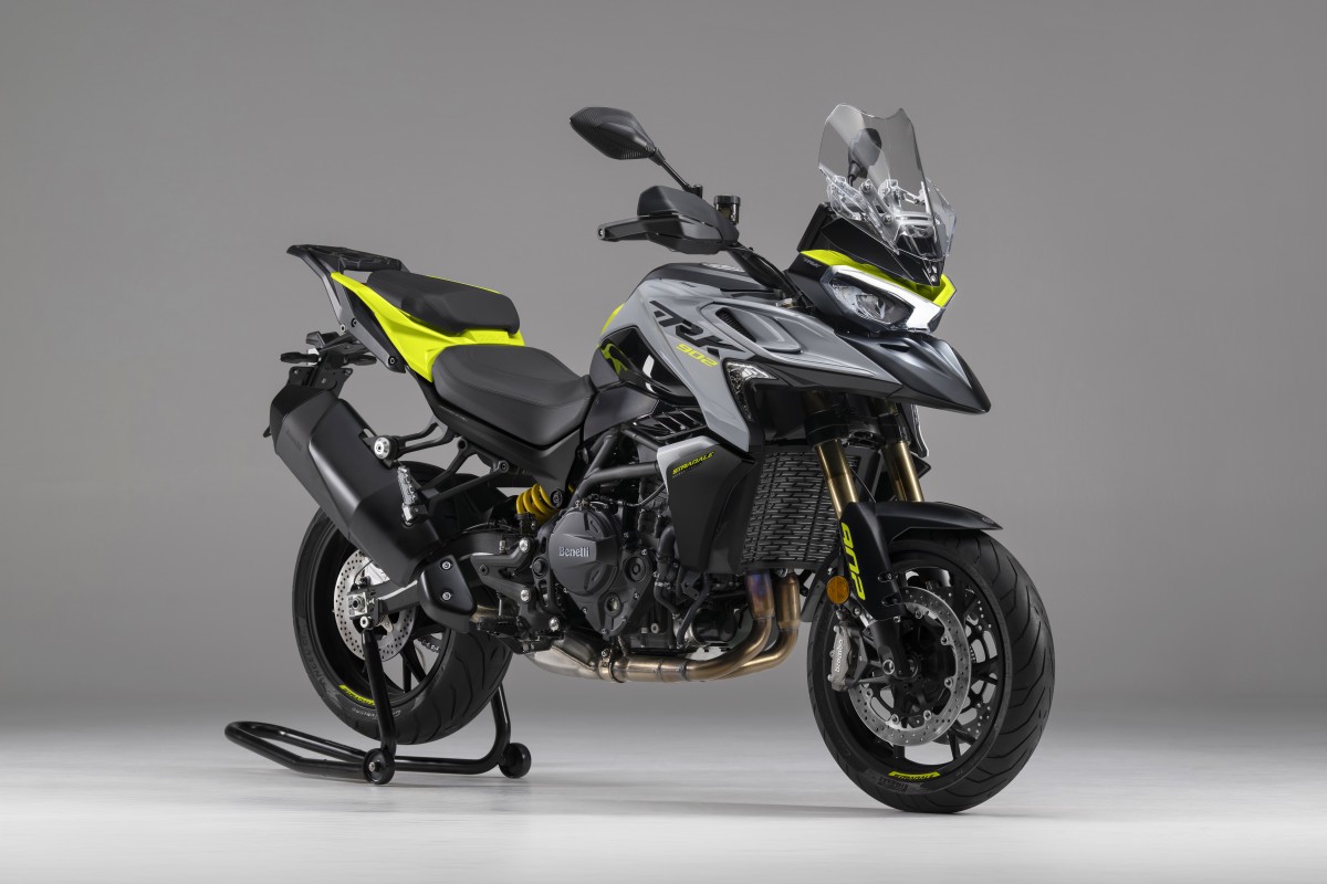 benelli-trk-902-stradale-1 - AutoBike Front three-quarter view of a gray Benelli adventure motorcycle with neon yellow accents, mounted on a rear stand in a studio setting. - AutoBike
