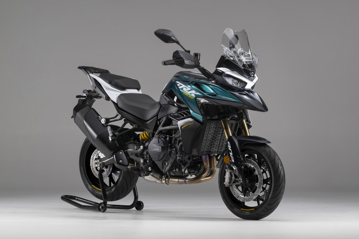 benelli-trk-902-stradale-2 - AutoBike Adventure motorcycle on a workshop stand in a neutral studio backdrop, teal and black with a clear windshield and gold front forks. - AutoBike