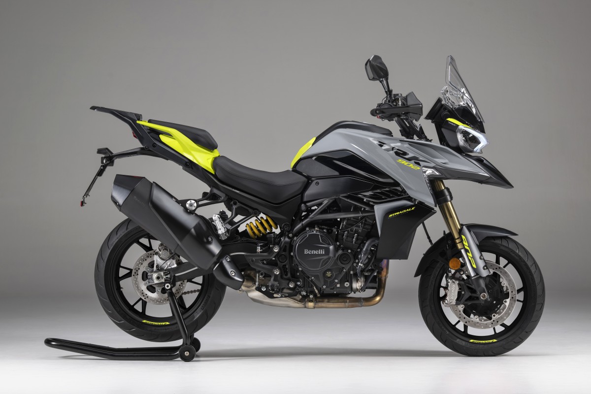 benelli-trk-902-stradale-4 - AutoBike Side view of a gray Benelli sport motorcycle with yellow accents on a paddock stand, showing engine and exhaust details - AutoBike