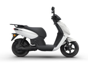 Side view of a white scooter with a black seat and rear luggage rack, shown from the left side.