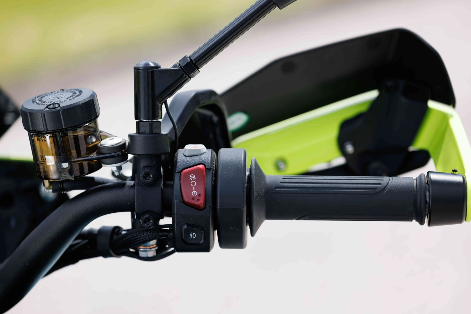 trk902_xplorer_095_optimized 1 - AutoBike Close-up of a motorcycle handlebar showing the brake reservoir, throttle grip, and control switches. - AutoBike