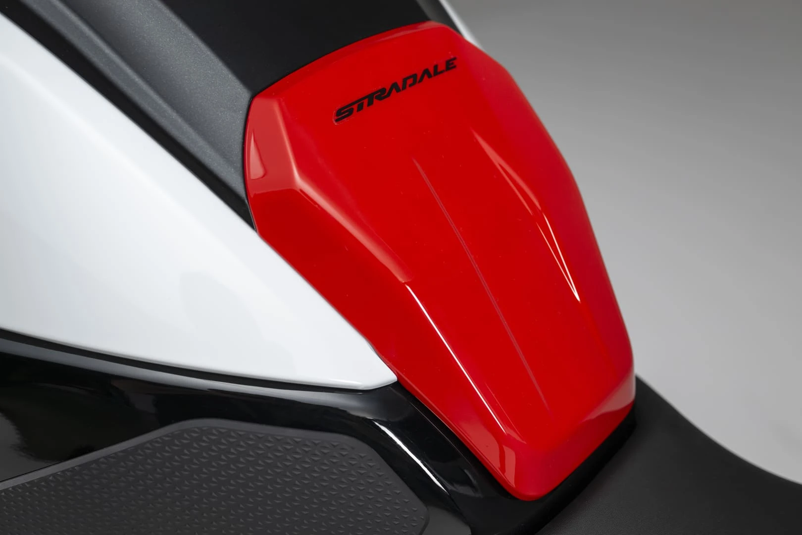 trk902stradale_18 - AutoBike Close-up of a glossy red motorcycle fairing with the 'STRADALE' branding, flanked by white and black body panels. - AutoBike