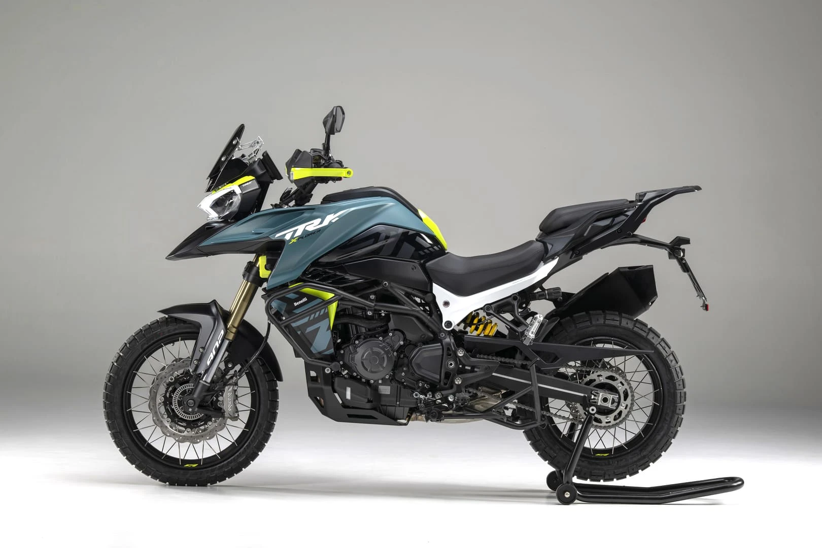 trk902xplorer_04 - AutoBike Adventure motorcycle on a stand in a studio, teal body with neon yellow accents and rugged knobby tires. - AutoBike