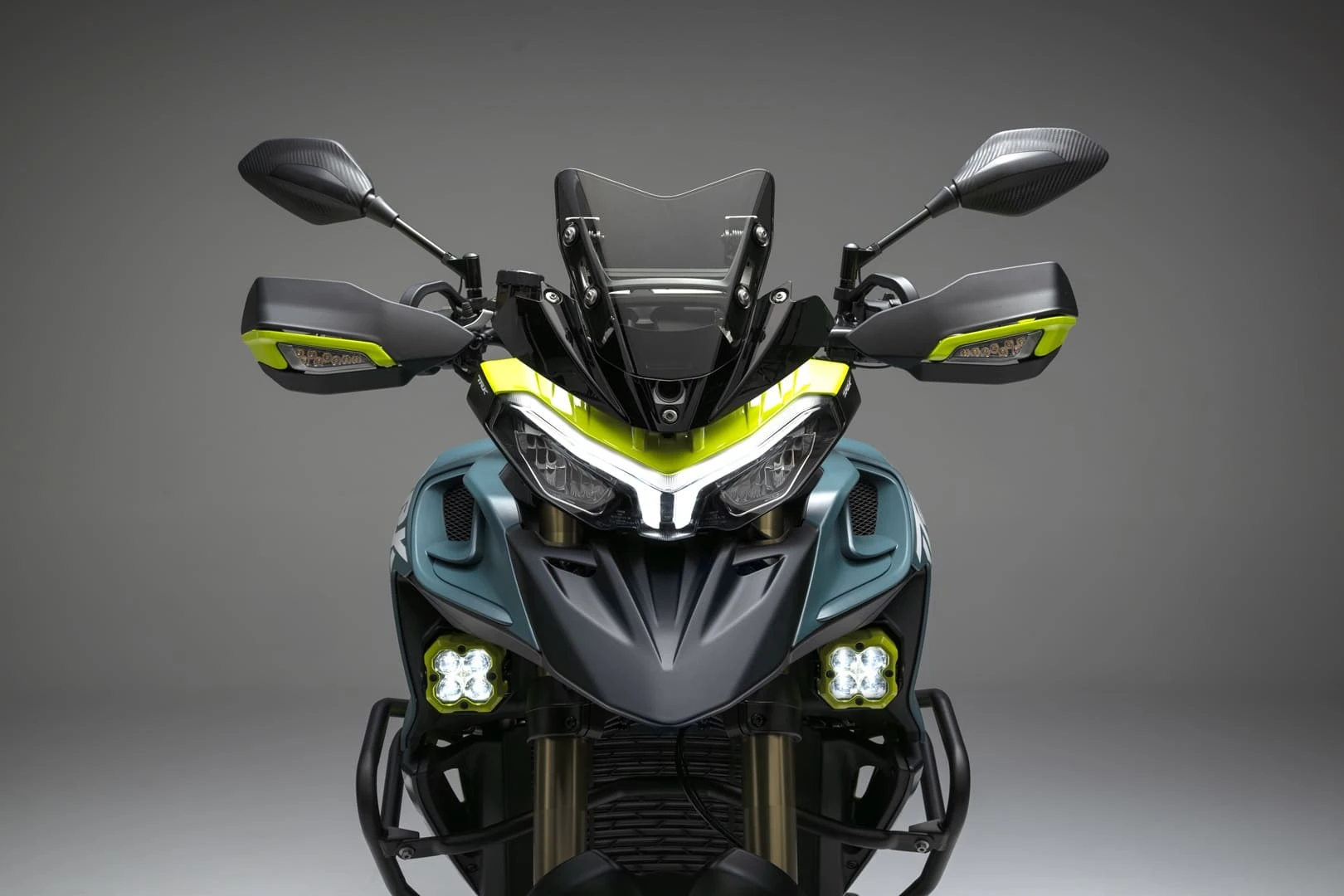 trk902xplorer_11 - AutoBike Front view of a modern sport motorcycle with neon-yellow accents, wide handlebars, and dual headlights on a gray backdrop. - AutoBike